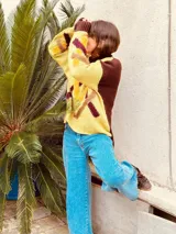 Sweater de punto color amarillo y marrón con diseño geométrico en el frente.