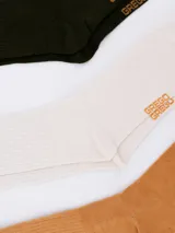 Pack de tres pares de medias deportivas de caña corta, con diseño a rayas en el borde superior y logo de la marca en el tobillo. Incluye un par negro con rayas blancas, un par blanco con rayas negras y un par gris con rayas blancas.