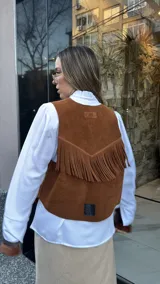 Chaleco marrón de cuero descarne con terminación en picos, tachas metálicas y flecos en la espalda.