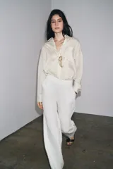 Camisa de manga larga con cuello solapa, a rayas verticales grises y blancas. Tiene un bolsillo de plastrón en el delantero y cierre frontal con botones.