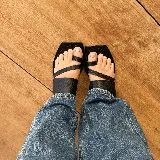 Sandalias planas de cuero color marrón con tiras cruzadas y base cuadrada negra.