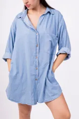 Camisa celeste de mangas largas con puños abotonados, cuello clásico y cierre frontal con botones.