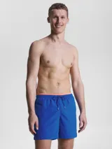 Bañador azul eléctrico de largo medio, con cintura elástica ajustable con cordón, ribete naranja en la cintura y logo de Tommy Hilfiger bordado en la parte trasera.
