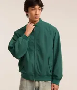 Campera bomber verde oscuro de poliéster con cuello alto con velcro, cierre por cremallera, bolsillos con solapa, manga larga ajustada y bajo ajustado.