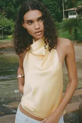 Top color amarillo claro de satén con cuello halter y espalda descubierta. Cierre trasero con botones ocultos.