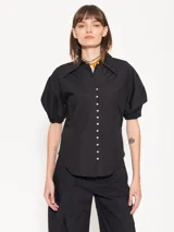 Camisa negra de popelina, de silueta amplia y diseño liviano. Incluye cuello clásico y cierre frontal con botones.