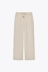 Pantalón de tiro alto color beige, con cintura elástica ajustable con cordones, bolsillos delanteros y pernera ancha.