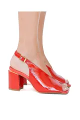 Zapato de charol rojo con punta cuadrada, escote en el empeine, tira trasera con hebilla y taco cuadrado.