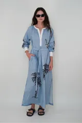 Vestido largo celeste con rayas verticales blancas, cuello mao con escote en V y lazo en la cintura. Presenta bordados de aves y palmeras en negro.