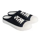 Zapatilla urbana negra con cordones blancos y suela blanca.