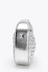 Bolso de mano plateado con efecto trenzado y asa corta. Incluye correa extraíble para usar como bandolera. Cierre con cremallera metálica.