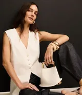 Chaleco largo color crema, con botones delanteros y lazo en la espalda.