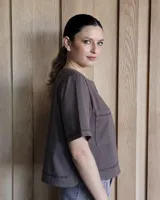 Remera negra con cuello redondo y mangas cortas, con detalle de pespuntes blancos en cuello, mangas, bolsillos frontales y ruedo.