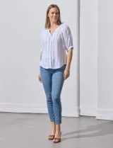Blusa blanca de algodón marca Zac & Rachel, con cuello a la base, escote en V, abertura central con botones y sisa con aplique calado.