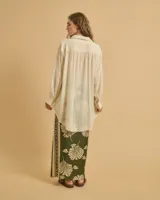 Camisa azul marino de manga larga con botones blancos, corte fluido y largo asimétrico.