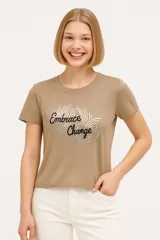 Remera manga corta color beige con estampado frontal con la frase "Embrace Change" en letras negras con contorno plateado.