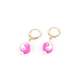 Aros colgantes dorados con dije de cilindro rosa con símbolo de yin yang blanco y perla colgante.