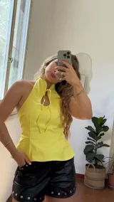 Top amarillo de gabardina elastizada, con cuello halter, corte ajustado y tiras decorativas en el frente.