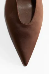 Zapatos destalonados de mujer con acabado satinado color marrón oscuro, punta fina y tacón de aguja bajo. Poseen una tira elástica en el talón.