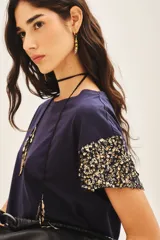 Remera de jersey 100% algodón color blanco, con cuello redondo y manga corta caída. Las mangas están completamente bordadas con lentejuelas tono sobre tono.