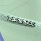 Ojotas Havaianas Slim Point color crema con contorno verde oscuro y logo en las tiras.