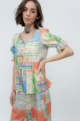 Camisa estampada con flores, de lino o popelina, con cuello en V y mangas cortas con volados. Se cierra con lazos en el frente.