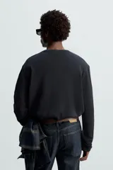 Camiseta blanca de manga larga con cuello redondo y textura cuadriculada.