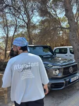 Remera rosa de corte recto con estampado en la espalda que incluye el texto "Itta Tours", "Tour", y nombres de ciudades como Ibiza, Madrid, Andorra, Barcelona y Formentera.