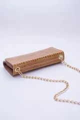 Cartera tipo sobre color beige con textura granulada y correa de cadena dorada.