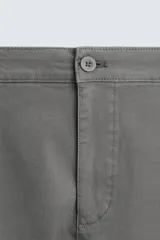 Pantalón chino color beige, corte skinny fit, confeccionado en tejido con mezcla de algodón y elasticidad. Cuenta con bolsillos frontales y traseros. Cierre frontal con cremallera y botón.