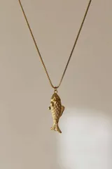 Collar dorado con cadena fina y dije de pez con textura de escamas.