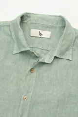 Camisa verde de lino con botones de madera, corte recto y mangas largas.