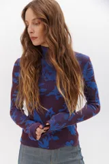 Polera de punto ajustada color azul con diseño de estrellas en tonos morados.