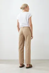 Pantalón recto color tostado con pespuntes verticales y cinturón de cuero marrón con hebilla dorada.