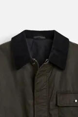 Parka relaxed fit color verde oscuro confeccionada en tejido de algodón con acabado encerado. Tiene cuello solapa combinado en pana negra, manga larga acabada en puño ajustable con botón a presión, bolsillos frontales de plastrón con solapa, bolsillo interior y cierre frontal de botonadura oculta por solapa.