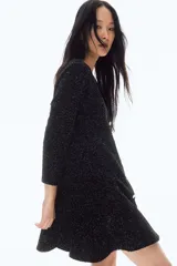 Vestido corto negro en tejido bouclé con hilos brillantes, escote en V, mangas tres cuartos y falda con vuelo.