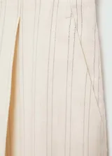 Pantalón de tiro medio color crema a rayas verticales finas, con dos bolsillos delanteros, cierre oculto de botón, gancho y cremallera, diseño recto y largo.