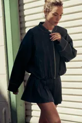Cazadora bomber de denim color gris oscuro, con cuello redondo, cierre frontal con cremallera metálica, bolsillos laterales y mangas largas con puños elásticos.