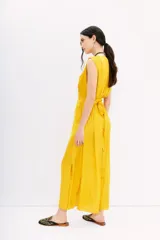 Vestido largo color amarillo mostaza, con escote en V, sin mangas y cintura elastizada con lazo.