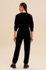 Conjunto deportivo negro de terciopelo compuesto por un buzo cropped de manga larga y un pantalón cargo con cintura ajustable y bolsillos laterales.