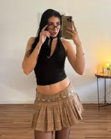 Conjunto de top halter negro con lazo al cuello y minifalda marrón a cuadros.