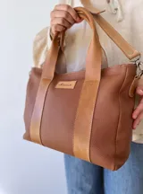 Bolso tipo tote de cuero color marrón con doble asa corta y correa larga extraíble.