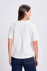 Remera blanca de manga corta con estampa de dos palmeras con una hamaca entre ellas y la frase "la siesta" en color rosa.