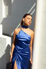 Vestido largo de satén azul eléctrico, con escote halter, cuello choker y falda con abertura lateral y detalle de nudo.