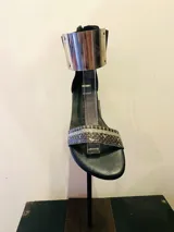 Sandalias gladiadoras negras con tira delantera con estampado de piel de serpiente, cierre trasero con cremallera y pulsera metálica dorada en el tobillo.