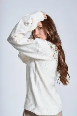 Sweater color crema de hilado frizado con cuello redondo y mangas largas. Presenta apliques de flores en los hombros y mangas.