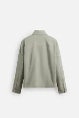 Sobrecamisa color arena de corte recto, con cuello solapa, cierre frontal con cremallera, manga larga con puños abotonados, dos bolsillos de plastrón con solapa en el pecho y dos bolsillos laterales en la costura de la cadera.