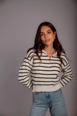 Sweater de punto color beige con rayas horizontales blancas, cuello polo con cierre de cremallera y mangas largas.