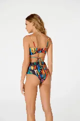 Traje de baño de dos piezas con estampado de plumas multicolores. El corpiño es strapless con aro dorado central y tiras finas que se atan al cuello. La bombacha es de tiro alto con aro dorado central.
