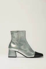 Botas cortas plateadas de cuero con puntera negra, taco cuadrado y cierre lateral.
